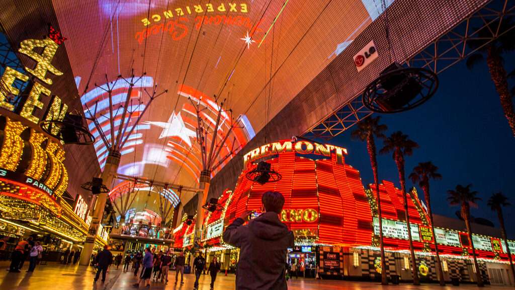 The lights of Fremont St. in Las Vegas. A man stands in the middle taking a picture