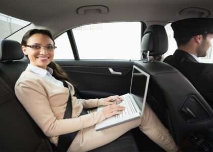 woman in the back seat of a car with a laptop