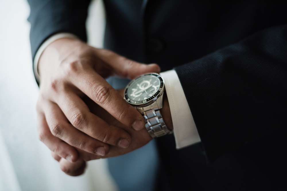 a man in s suit looks at his watch.